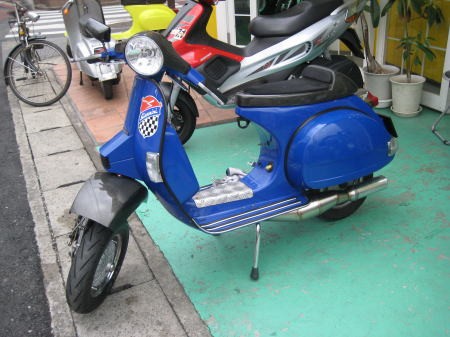 ドロップハンドル仕様の青いベスパPXが店舗前に停車している