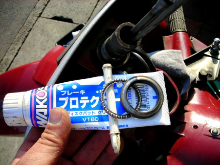 ベスパのハンドルコラム整備中に使用するブレーキグリスとベアリング部品の写真。