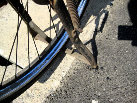 アスファルトにめり込んだ自転車のスタンド
