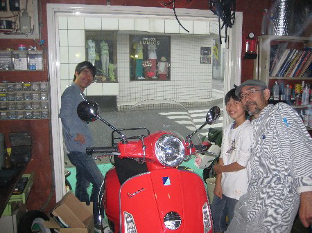 大雨でK.B.SCOOTERSに雨宿りした人々と赤いベスパ