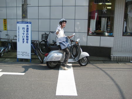 納車されたばかりのベスパ50sに跨がりピースサインをするオーナー。
