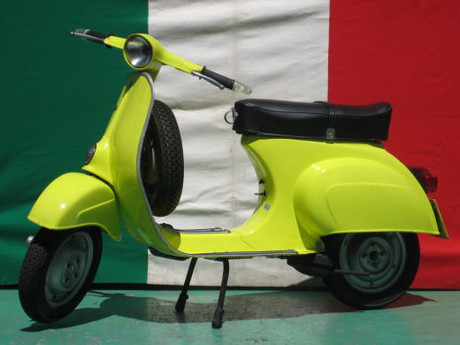 イタリア国旗を背景に撮影された黄色いベスパ50S