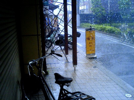 商店街の軒先で雨宿り中の自転車と風景