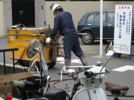 作業員が機械を使って道路にカッターを入れている様子。