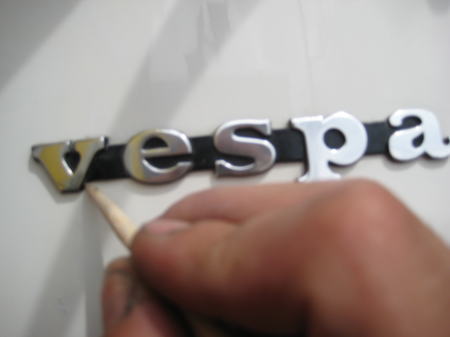 vespaエンブレム周辺に残ったWAXを竹の割り箸で拭き取る作業。