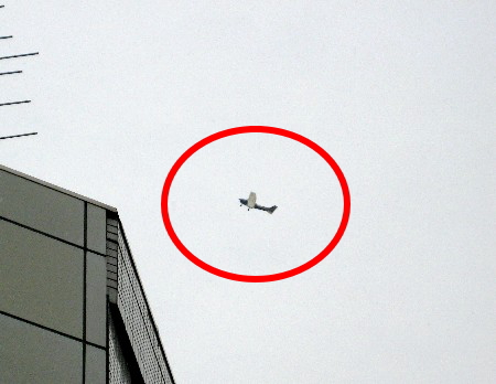 空を飛ぶ小型セスナ機とビルの角
