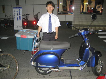 青いベスパのリアに大型ボックスを積んだ通勤スタイル