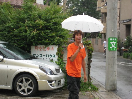傘をさして笑顔でこちらを見つめるK.B.SCOOTERSのKさん