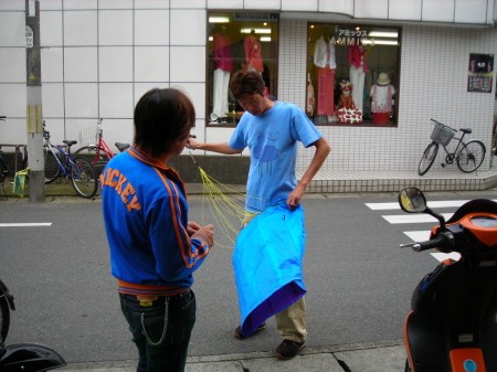 伝説のベスパ乗りとKがカイトを手に会話している様子