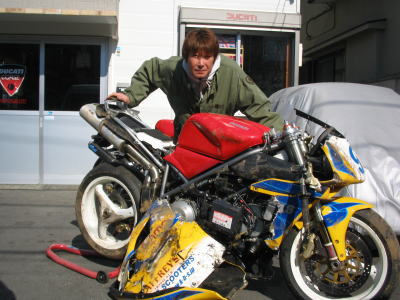 赤い車体のバイクの前に、激しく破損した黄色と青のレースバイクが並ぶ