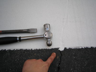 タガネとハンマーで横断歩道のはみ出した白線を削る作業の様子