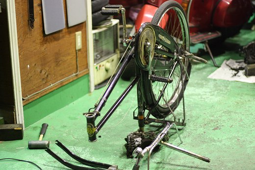 フロントフォークが外され、逆さに立てられた整備中の古い自転車。