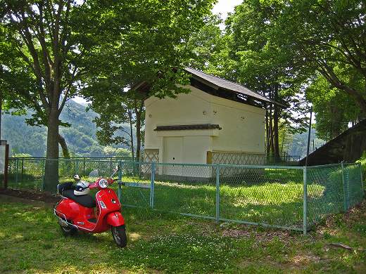 キャンペーン告知中の赤いベスパGTS250ieと倉庫風の建物