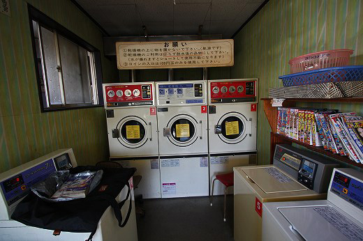 黄色い壁に掛けられたツナギと緑の郵便ポスト