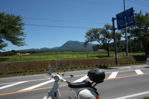 ベスパと筑波山のツーショット。夏空の下、田園地帯を背景にした県道沿いの風景。