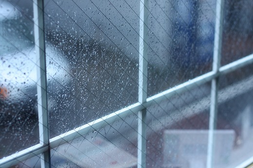 雨粒が打ちつけるワイヤー入りの窓ガラス