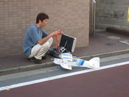 歩行者天国となった道路脇でラジコン飛行機の準備をするK氏