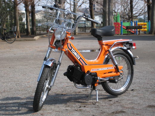 オレンジ色のTOMOS Classic Ⅰを公園で斜め前から撮影した全体写真
