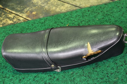 表皮が大きく破れた黒いベスパのシート。