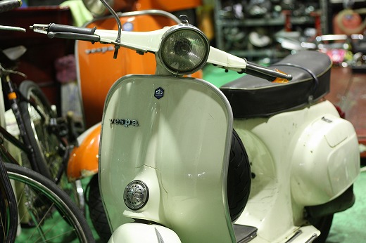 夜の街路樹の下に停められたオレンジのVespa125ET3