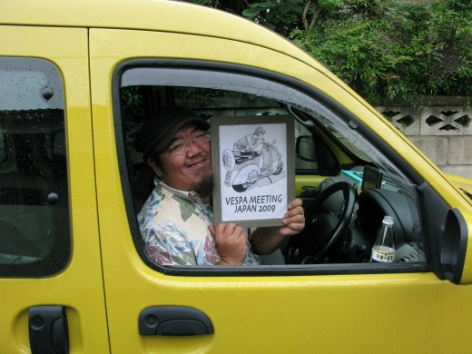 黄色い車内でフライヤーを掲げる永遠の独身貴族「vespa野郎」さん
