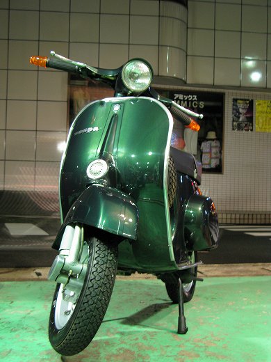 🛵 夜の街灯に照らされる濃緑のベスパ50sを正面左側から撮影した写真