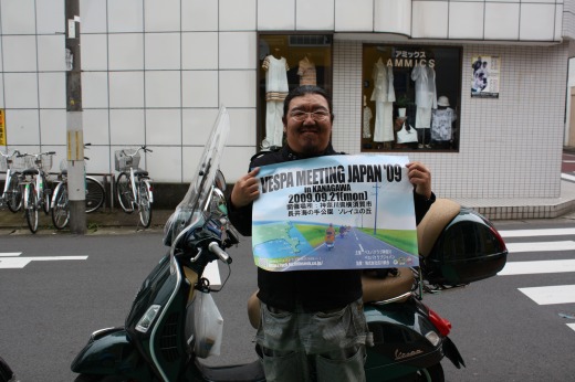 ベスパミーティング2009のポスターを掲げる来店者