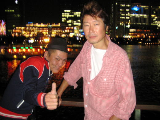 東京湾の夜景を背に記念写真に収まる男性二人の姿