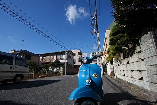 冬の青空の下、坂道に佇む青いベスパ