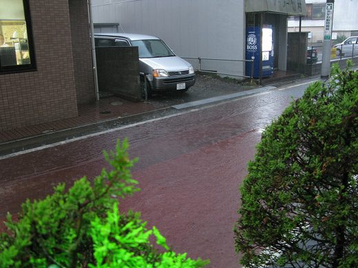 土砂降りの中、交差点脇に停められた青いベスパ