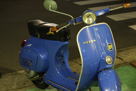 夜の交差点近くに停められたブルーのVespa50S