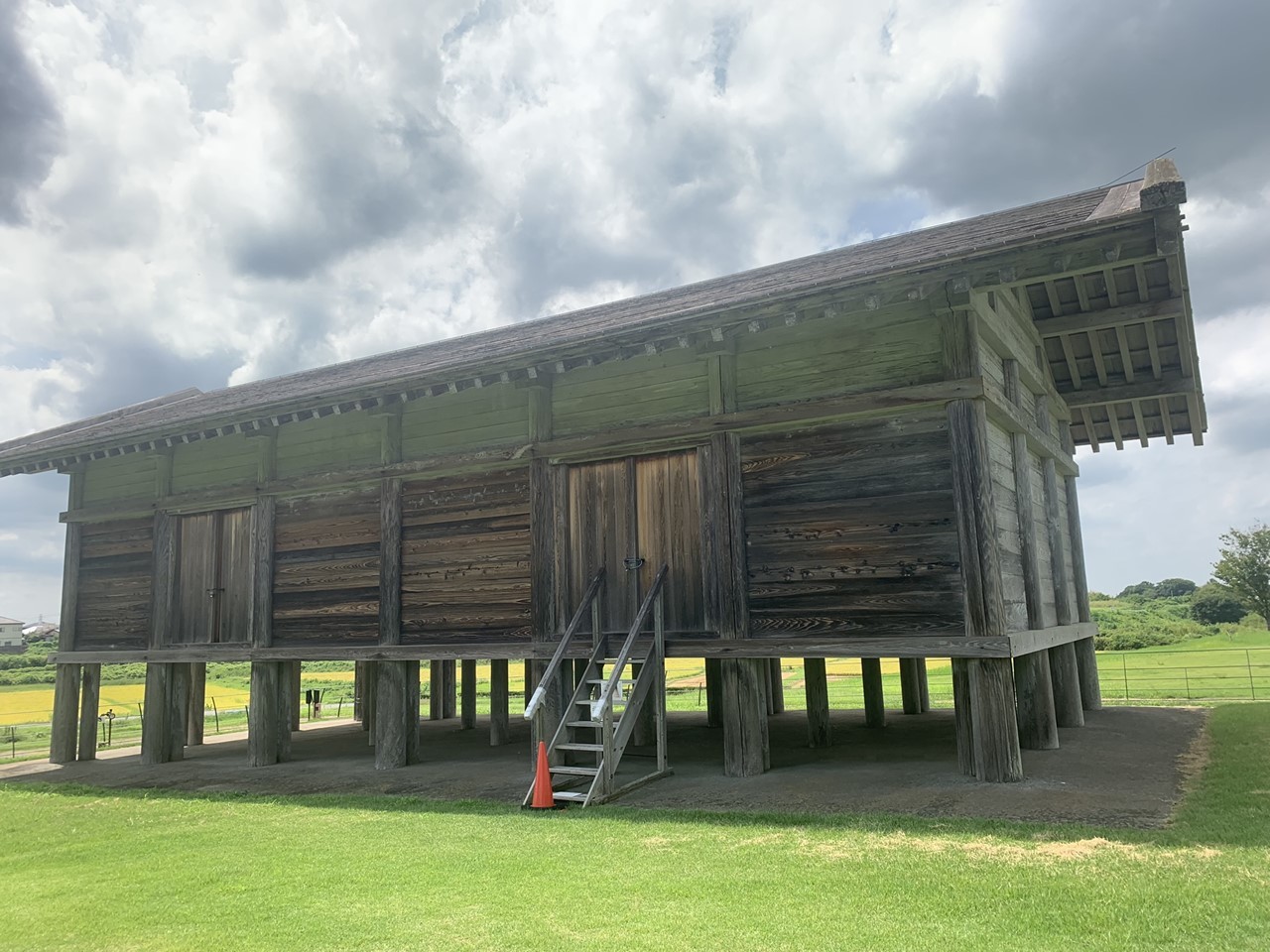 高床式の建物を再現した平沢官衙遺跡の一棟。空と緑に囲まれた風景。