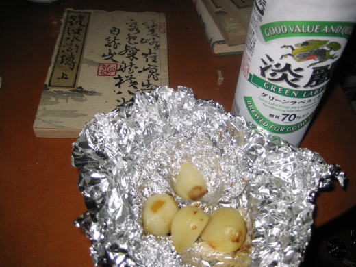ニンニクのホイル焼きとビール缶の晩酌風景