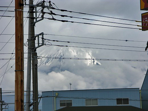 雲の切れ間から山頂だけが見える富士山の遠景写真