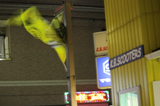 店脇に掲げられたレイソルの旗が強風で大きくなびいている夜の写真。