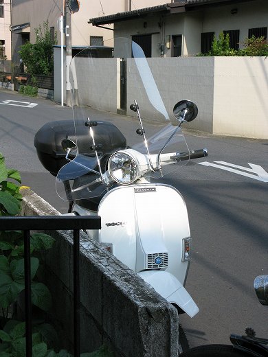夕暮れ時に洗車された白いベスパと風防が輝く姿