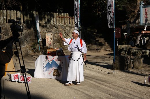 神社の境内で「がまの油売り」の口上を披露する人物