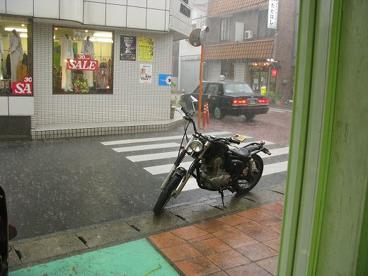 大粒の雨に打たれる路上のバイクと交差点⛈️