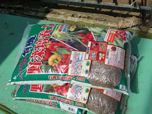 野菜培養土の袋が2つ、地面に置かれている。