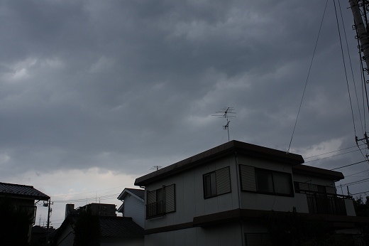 雨が降り出しそうな曇り空と住宅街の屋根
