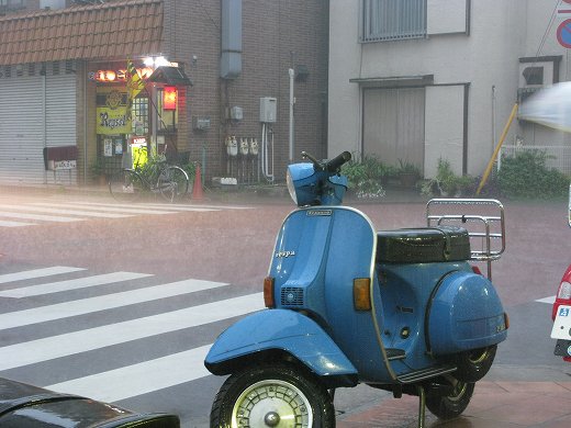 雨に濡れる裏通り、自販機と濡れた路面が静けさを漂わせる