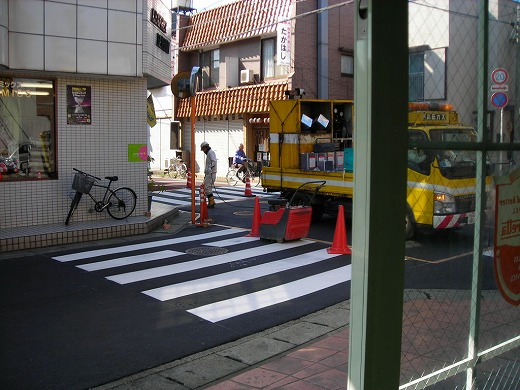 店舗前で進行中の横断歩道の白線ペイント工事風景