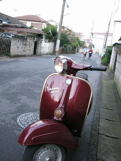 路地に停められたボルドー色のクラシックベスパ、前方から撮影。