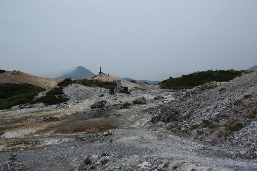 火山性の大地に点在する遺構。奥には石像や塔のようなシルエットが見える神秘的な風景