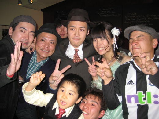 結婚パーティーで撮影された新郎新婦と仲間たちの集合写真