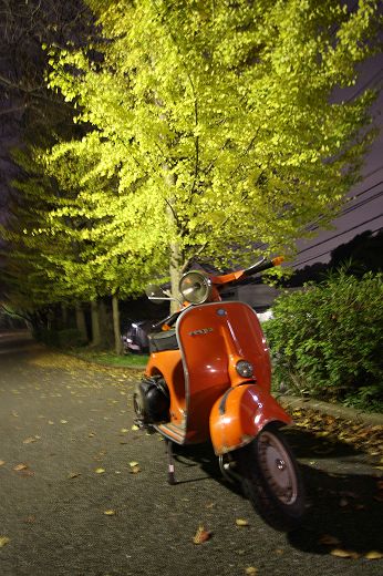 店内に展示された白いVespa125GTRとその奥に見えるオレンジの車体