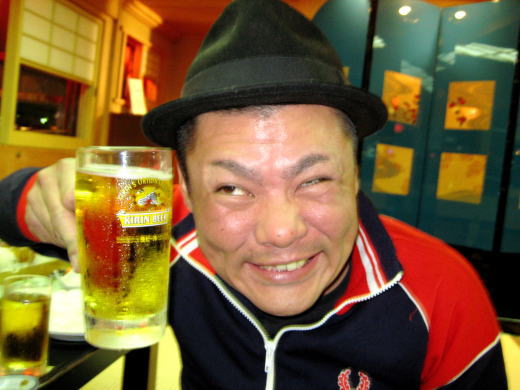 帽子をかぶった男性が大きなグラスで乾杯する笑顔のアップ