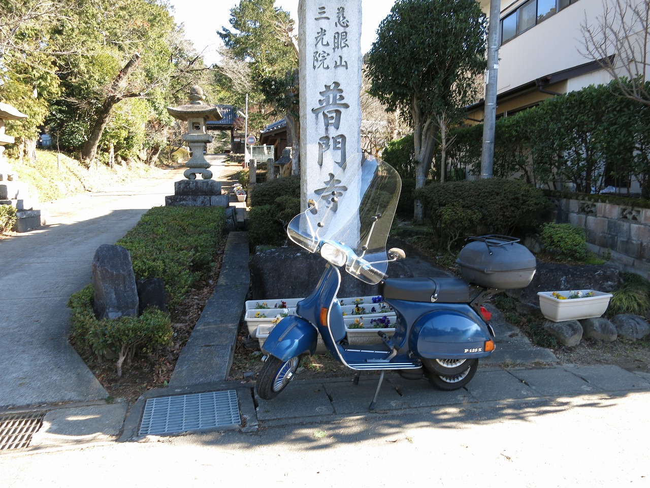 古い道標が立つ町角に停められたベスパ