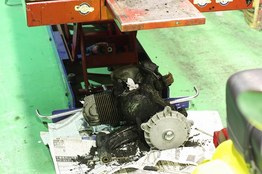 整備リフトの下に置かれた、分解途中のベスパ125GTRエンジン。