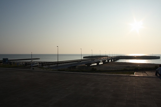 道の駅岩城の海上桟橋と夕日に照らされる港の風景